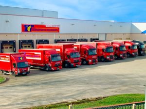 Flotte de camions rouges modernes de Transports Toussaint alignée devant leur bâtiment à Le Perray-en-Yvelines, illustrant leur capacité de transport routier et leur présence logistique en Île-de-France.
