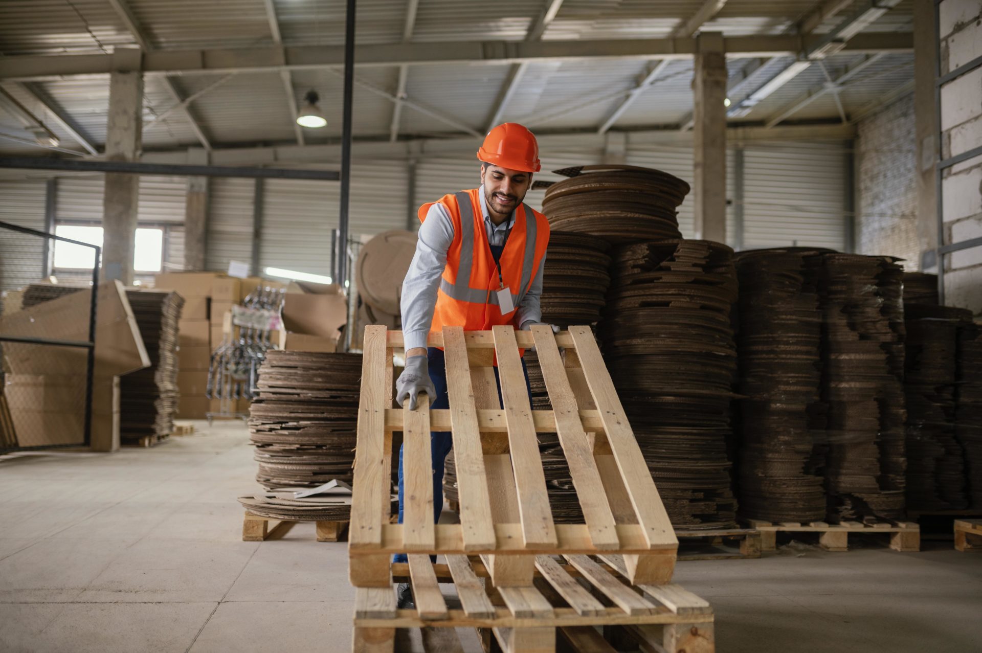 Opérateur logistique manipulant une palette bois dans un entrepôt industriel