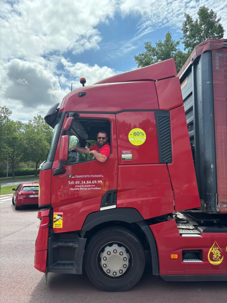 Camion Transports Toussaint avec conducteur au volant, véhicule floqué et étiqueté -60% de CO₂